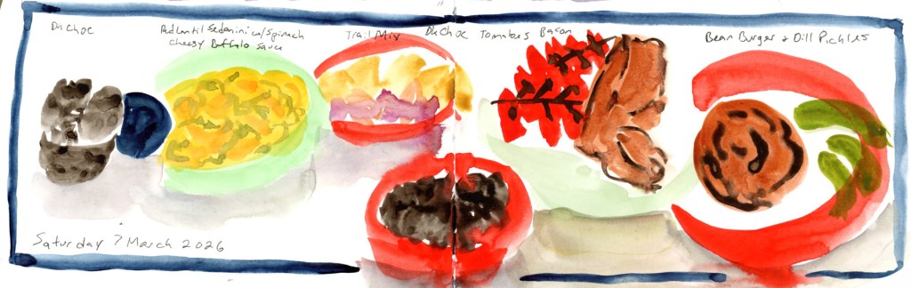 Watercolor and ink food sketch on a double page spread, Saturday 7 March 2026, with a blue border. A row of food items stretches across both pages: dark chocolate and a navy oval on the far left, followed by a green bowl of yellow pasta, a red-rimmed bowl of trail mix, a small dark bowl of chocolate, a sketch of tomatoes on the vine with strips of vegan bacon, and a red-rimmed plate with a bean burger and dill pickles. Food labels are handwritten above each item, with the date written at the bottom left.